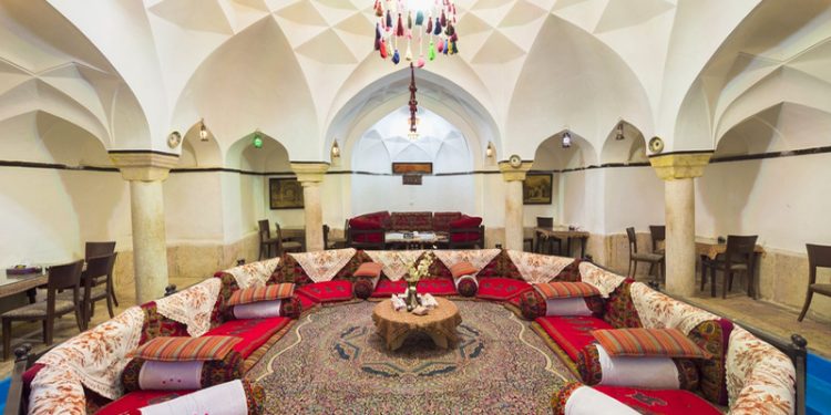 alt="فضای سنتی و دکور سفره‌ خانه‌ ها و قلیون‌ سراهای کرمان با تخت‌های چوبی و پشتی‌های ترمه"